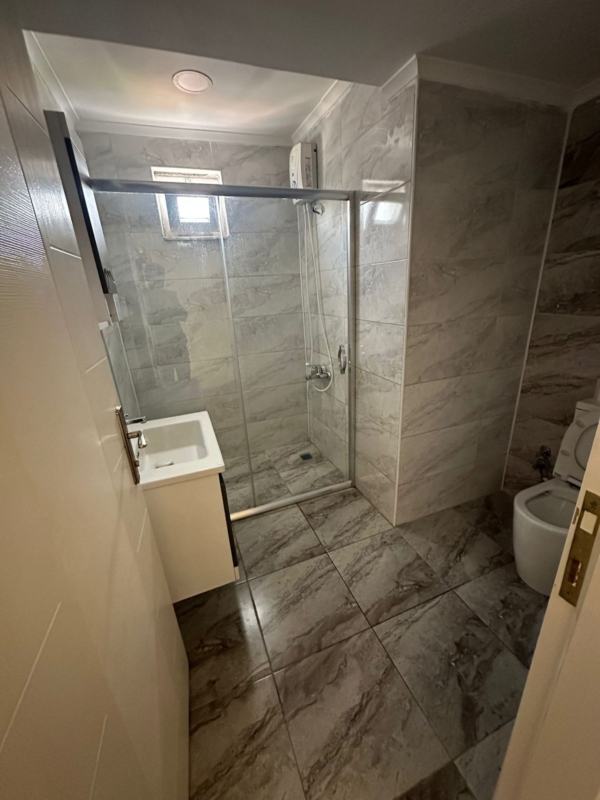 Modern marble-tiled bathroom with glass shower enclosure in the Lara Duplex apartment